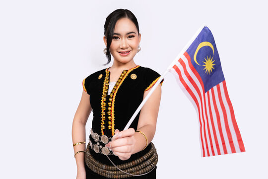 Smiling Sabahan Woman Extending Malaysia Flag Forward in Kadazan Dusun Dress