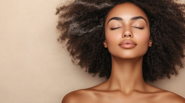 A woman sits calmly with her eyes closed, showing a content expression. Her curly hair frames her face against a neutral background. The image conveys a sense of relaxation.