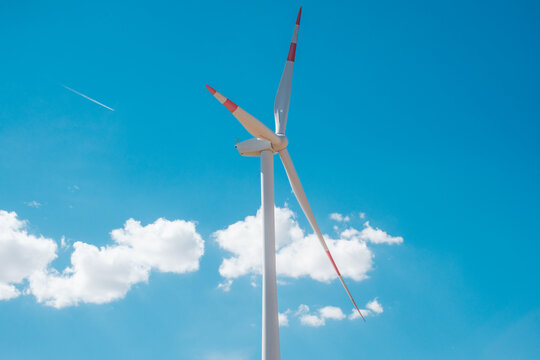 View of a wind turbine at the Wind farm Alibunar set against a bright blue sky with scattered white clouds Alibunar, Vojvodina, Serbia.