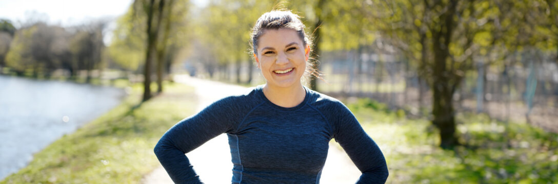 Portrait auf a cheerful and happy smiling woman wearing sportswear outdoors in nature, panoramic view	
