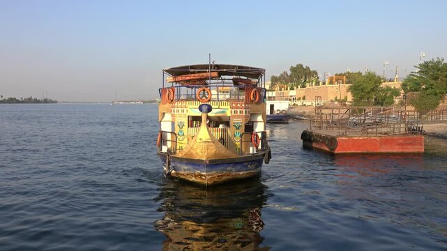 View of a traditional Nile boat sailing on the river with decorative patterns and life rings in Luxor Governorate, Egypt.