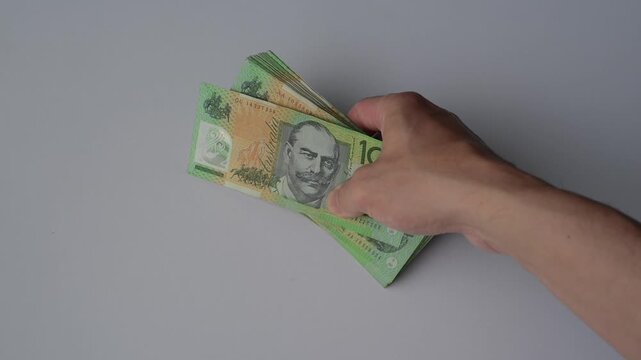 Saving money investment and financial planning concept. A man counting hundred and fifty Australian dollar bills in cash on hand as payment, savings, business funds, dividends, wealth.