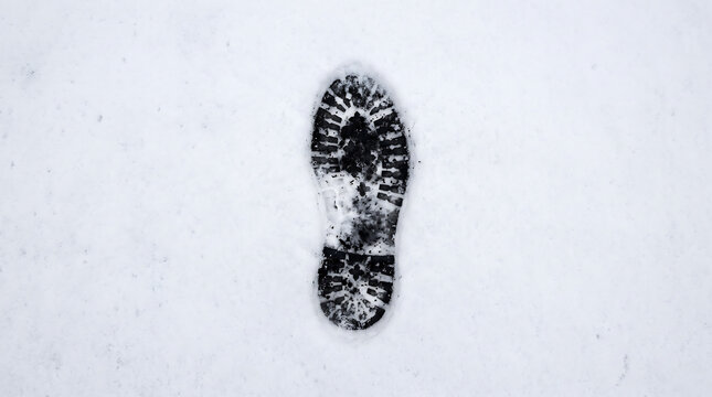 A single, clear boot print leaves an impression in fresh, undisturbed white snow, highlighting winter activities and individual presence.