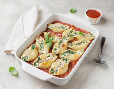 Delicious baked pasta shells stuffed with creamy ricotta and fresh spinach, served in a rich tomato sauce, garnished with basil leaves and almond slices