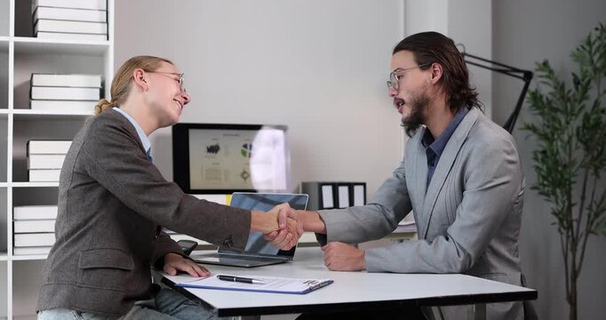 Business partners shaking hands at an office desk, finalizing a successful agreement, partnership, or deal after a productive meeting and interview in a modern corporate setting