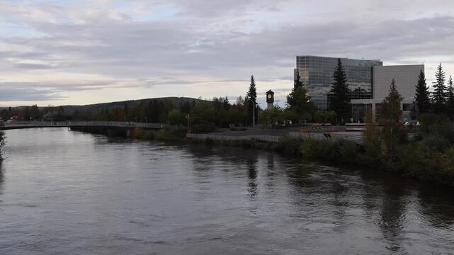 View of the Chena River flowing past the clock tower and modern architecture in Fairbanks, Alaska, United States.