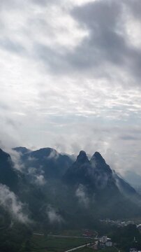 Vertical Video: White cloud sea above karst mountains with village houses scattered below