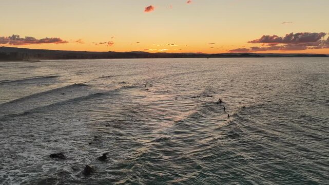 Sunset surfers at Snapper Rocks with the Surfers Paradise skyline beyond, aerial drone view, Gold Coast, Queensland Australia