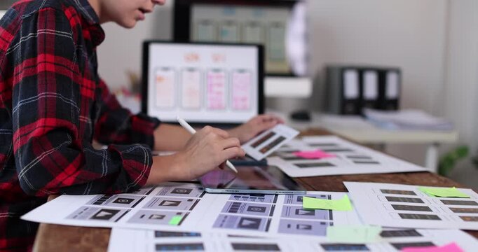 Woman ux designer working on mobile application user interface layout, creating wireframes and app prototypes on a computer at a creative office desk