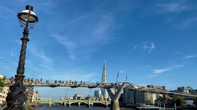 London Embankment people crossing Millennium Bridge over Thames below Shard