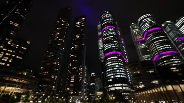 View of the illuminated skyscrapers of Barangaroo at night, featuring modern glass architecture with vibrant purple lighting in Sydney, New South Wales, Australia.