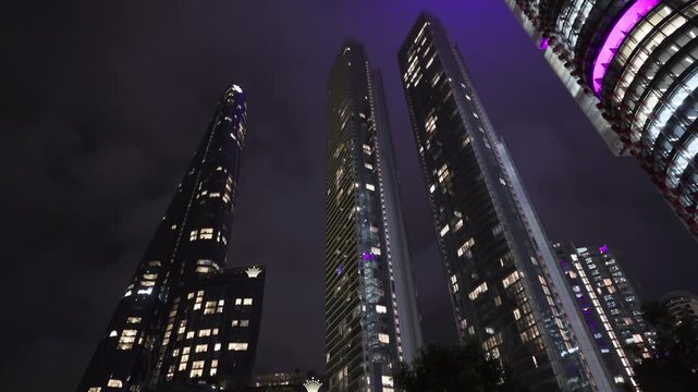 View of illuminated Crown Sydney skyscrapers at night with trees in the foreground in Sydney, New South Wales, Australia.
