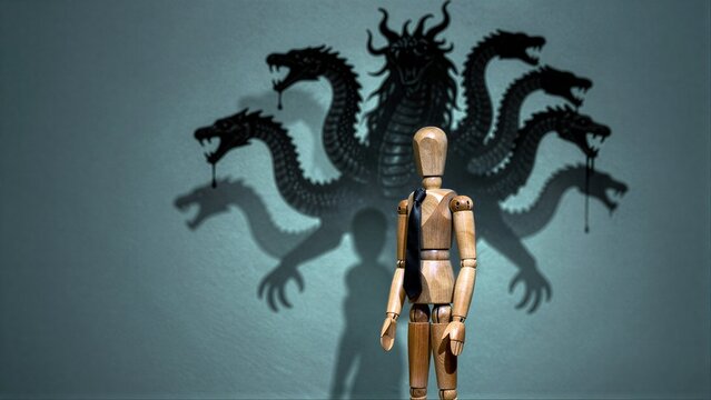Wooden mannequin stands before shadowy, menacing multi-headed dragon projection.