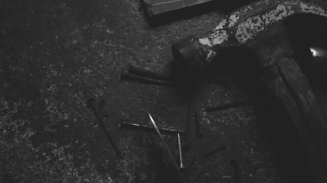Vintage rusty hammer and scattered nails on textured dark concrete floor