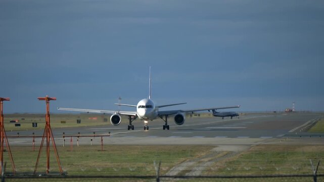 Front View of an Airliner on the Runway with a Propeller Airplane Crossing Behind