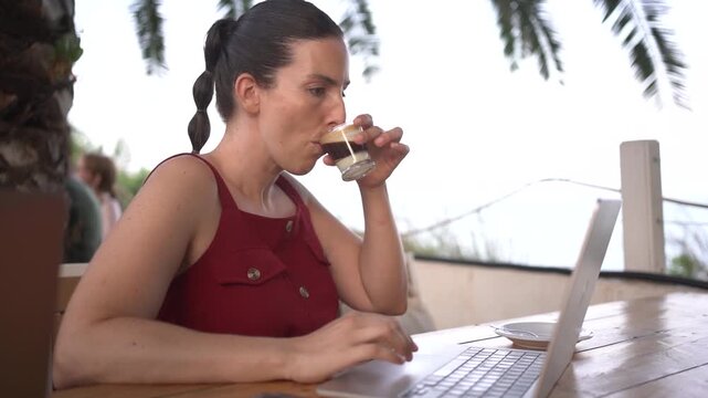 young digital nomad women doing remote work on laptop at outdoor terrace cafe bar, happy millennials in their 30s digital nomad lifestyle