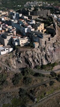 Vertical, aerial view of the Castelsardo, a medieval town in northern Sardinia (Sassari province) on the Gulf of Asinara. It features cascading, colorful houses and a historic fortress.