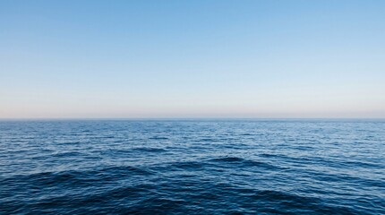 Obraz premium Vast minimalist seascape with deep blue waves meeting a clear gradient sky at a straight horizon, calming infinite marine atmosphere