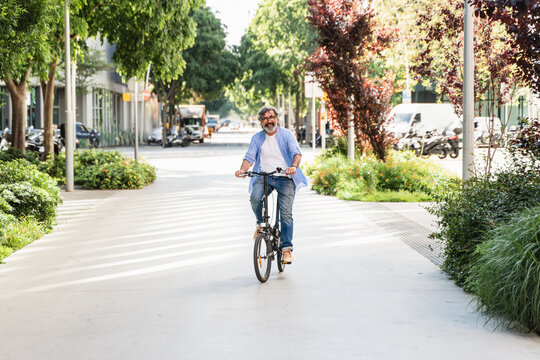 Senior man riding bicycle in the street. Active retired urban lifestyle