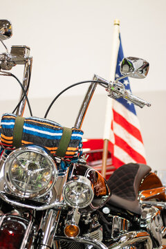 Krakow, Polska - September 06, 2026: Custom motorcycle with chrome details and colorful seat cover, American flag displayed in the background, showcasing classic design elements