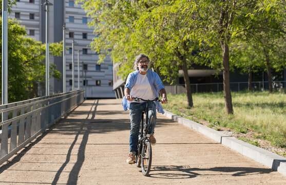 Senior man riding electric bicycle in urban park, enjoying sustainable transportation and healthy lifestyle