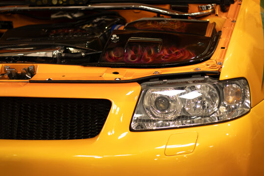 Krakow, Polska - September 06, 2026: Yellow car hood with custom flames design and visible engine components, showcasing automotive detailing and craftsmanship in a garage setting