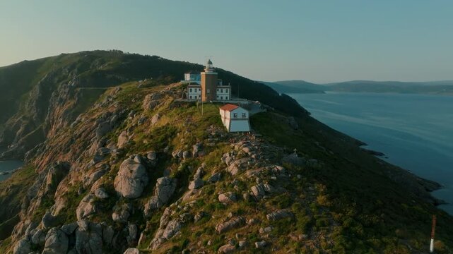 Vast, breathtaking aerial vista of the iconic Cape Finisterre lighthouse perched dramatically upon rugged, windswept cliffs at the edge of the Atlantic, embodying the serene and emotional conclusion