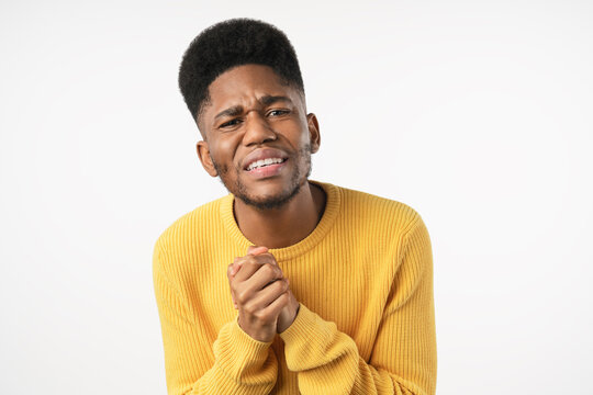 Guilty young man keeping hands together and begging for mercy, asking for help isolated over white background, apologetic male expressing regret, hope, forgiveness, request and emotional plea concept
