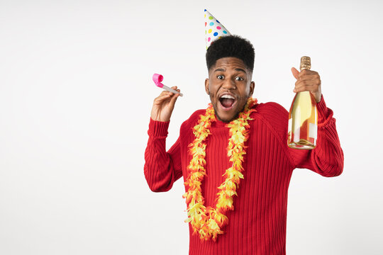 Funny young African man wearing birthday hat and holding bottle isolated over white background, cheerful male celebrating birthday, party, holiday, festive mood, fun, joy and special occasion concept