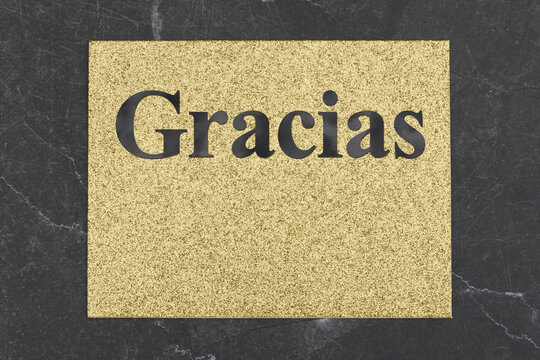 Thank you Gracias Spanish message on gold glitter greeting card on black stone
