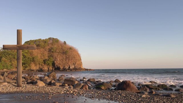 Christian background featuring a cross, mountains, and a rocky beach with rolling waves.