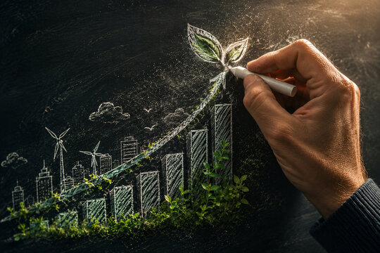 Hand drawing an upward growth chart with a green plant on a chalkboard, symbolizing sustainable business, renewable energy and environmentally responsible economic development