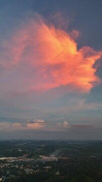 Vertical Video: Fiery red cloud mass hanging over a karst village at sunset