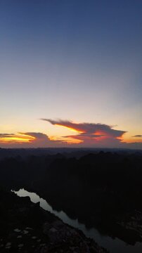 Vertical Video: Colorful sunset clouds glowing over karst mountains and river landscape