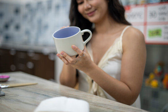 Woman holding ceramic mug appreciating handmade craft