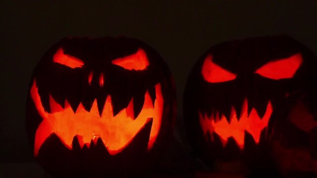 Inside the pumpkin, a reddish-orange light glowed brightly in the darkness, revealing carved, piercing eyes and a mouth filled with sharp, menacing teeth.