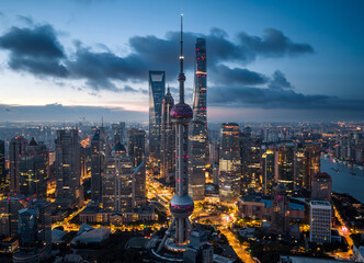 Obraz premium Aerial view of the Shanghai CBD skyline at dawn, featuring illuminated skyscrapers against a vibrant sunrise, symbolizing a global economic hub.