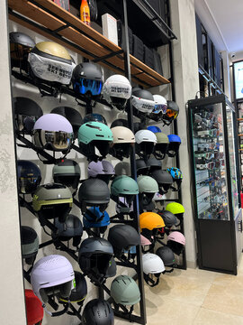 A display of various helmets arranged on shelves in a store. The helmets feature different colors and designs, showcasing options for skiing and snowboarding. 