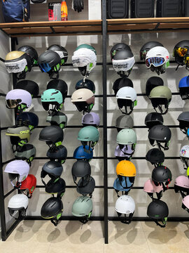 A display of various helmets arranged on shelves in a store. The helmets feature different colors and designs, showcasing options for skiing and snowboarding. 