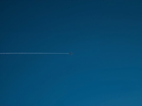 Generative AI captures a distant aircraft leaving a vapor trail in clear blue sky
