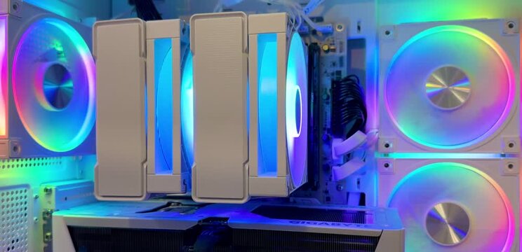 White desktop computer case with colorful RGB fans, a large CPU cooler, and graphics card visible inside. Gaming hardware, custom PC, RGB lighting, computer technology.