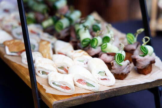 A display stand set up with appetizers and canapes for a banquet table, a buffet for an outdoor celebration, and on-site catering services