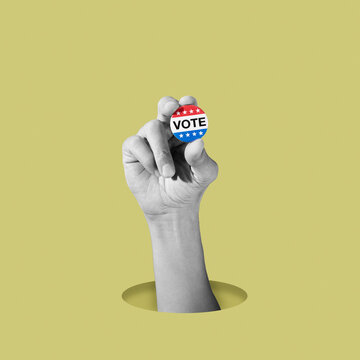black and white man holding a colorful vote badge