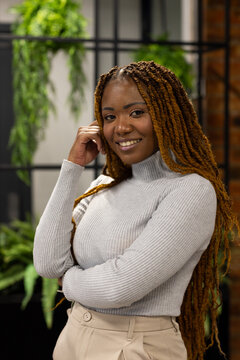 Mid adult African female wearing turtleneck and beige pants standing in studio with brick wall