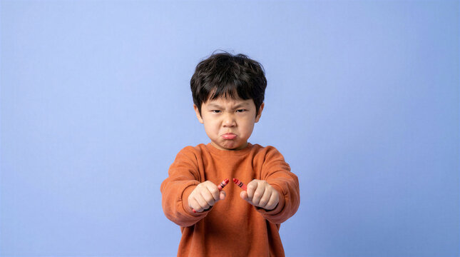 Young boy frustrated holding a broken red crayon against a plain background