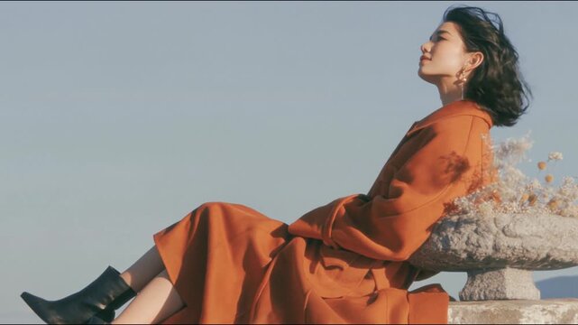 Cinematic Fashion Portrait of Woman in Brown Coat Sitting Outdoors