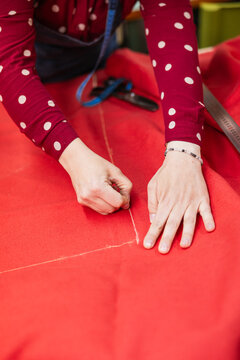 Hands marking red fabric with chalk for upholstery
