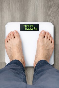 A person stands on a scale with their feet on the platform, measuring their weight