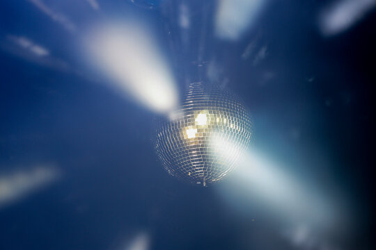 Sparkling disco ball reflecting bright lights in a dark nightclub or party venue with dynamic motion blur effect.
