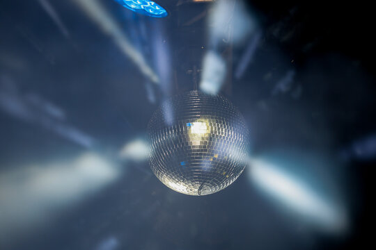Sparkling disco ball reflecting bright lights in a dark nightclub or party venue with dynamic motion blur effect.
